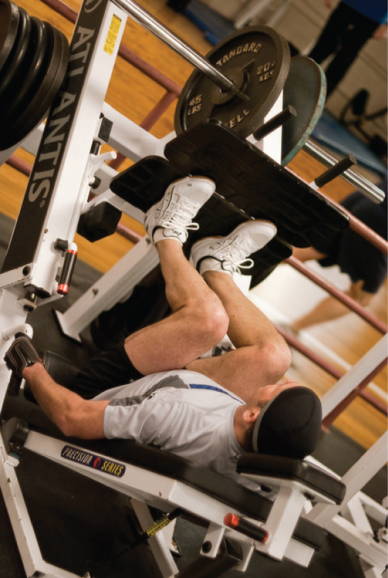 This photo shows a man exercising on a leg press machine at a gym.