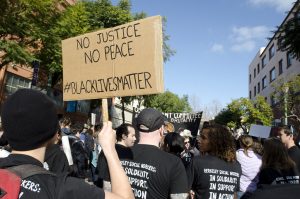 Marchers carrying sign reading No Justice No Peace #Black Lives Matter