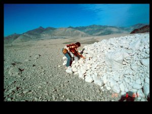 Man sampling a large mass of whitish boulders