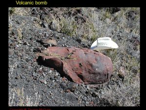 Photo of a large, "leathery" looking rock, a volcanic bomb, with a hat next to it for scale.