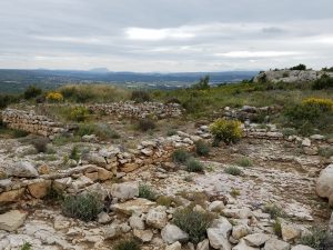 Stone ruins in a landscape covered by bare rock and scattered shrubs