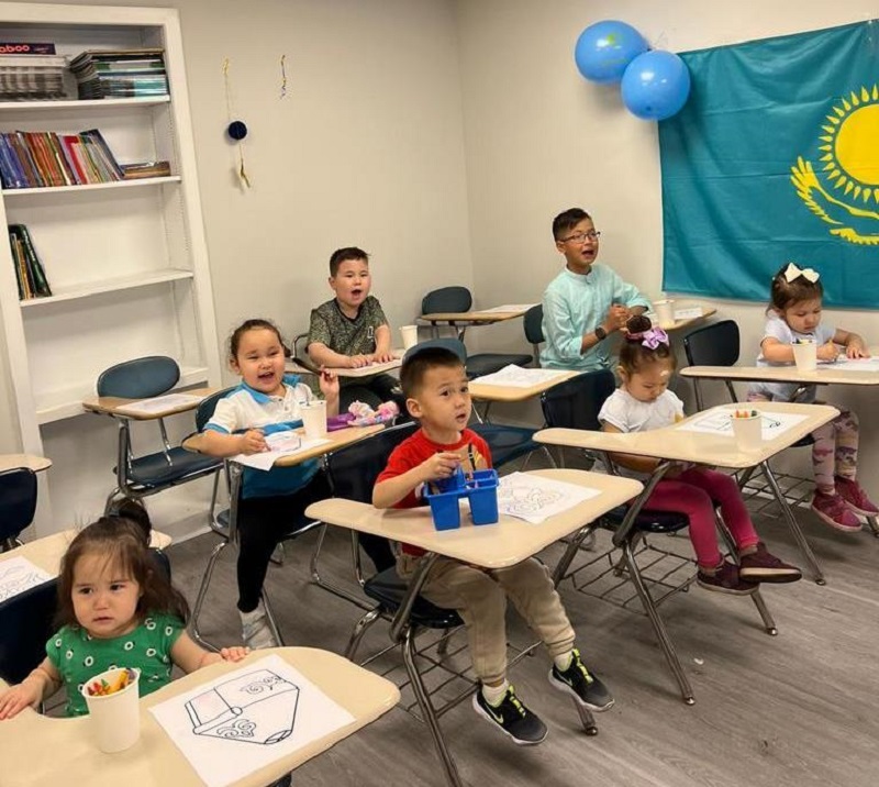 children in a room with a Kazakh flag and coloring a Kazakh yurt