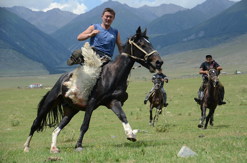 3 men on horses, one is holding a sheep carcass